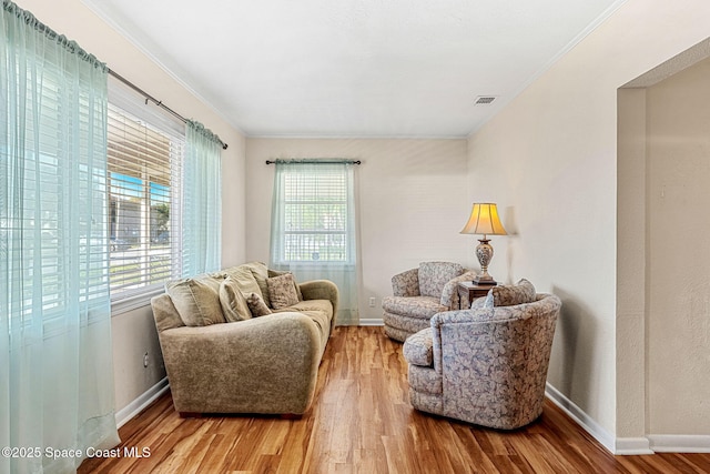 sitting room with ornamental molding and hardwood / wood-style floors