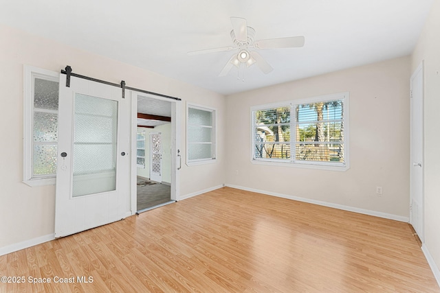 unfurnished bedroom featuring ceiling fan, light hardwood / wood-style floors, and a barn door