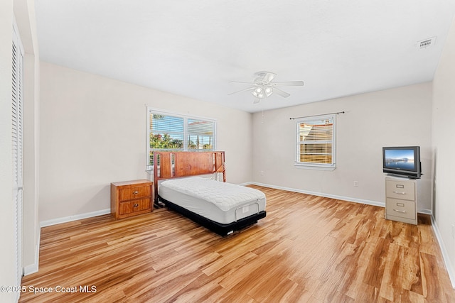 bedroom with light wood-type flooring, ceiling fan, and a closet