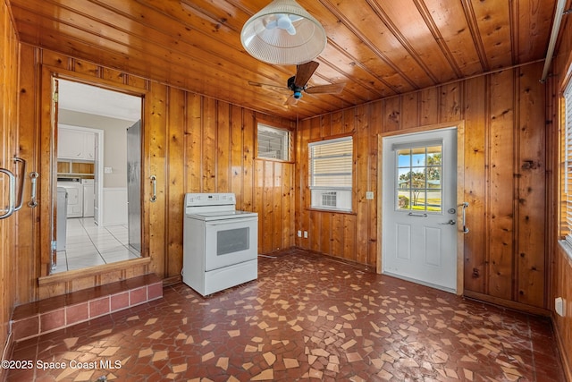 interior space featuring wood ceiling, washing machine and clothes dryer, wooden walls, ceiling fan, and cabinets