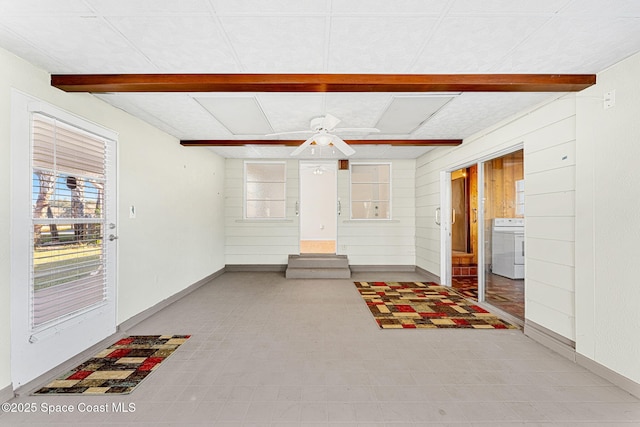 interior space with ceiling fan, beam ceiling, wood walls, and washer / clothes dryer