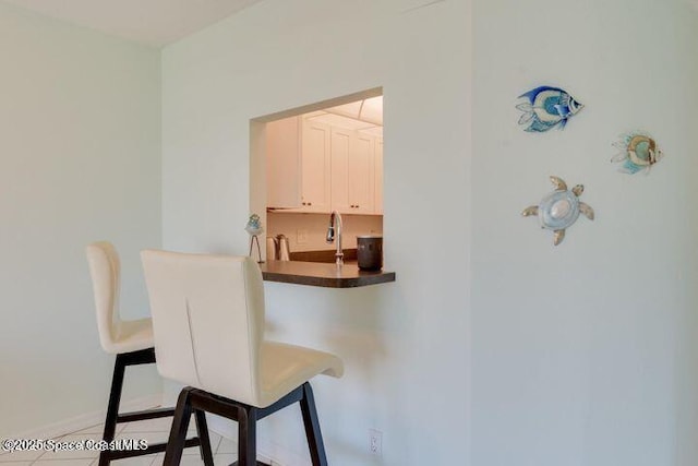 bar featuring white cabinets and light tile patterned floors