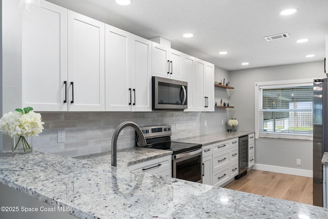 kitchen with light stone counters, white cabinets, and appliances with stainless steel finishes