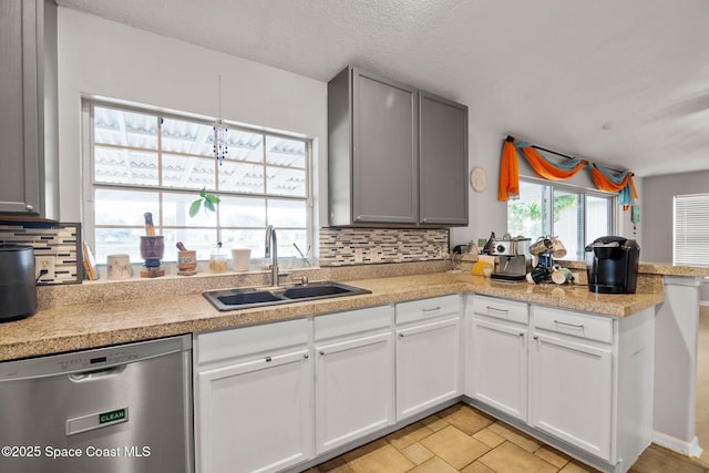 kitchen featuring a textured ceiling, dishwasher, tasteful backsplash, sink, and light tile patterned flooring