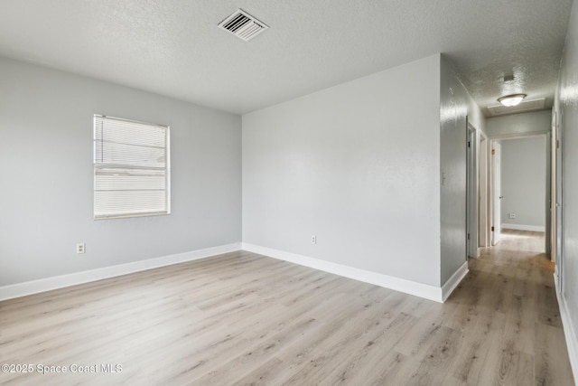 spare room featuring a textured ceiling and light hardwood / wood-style flooring