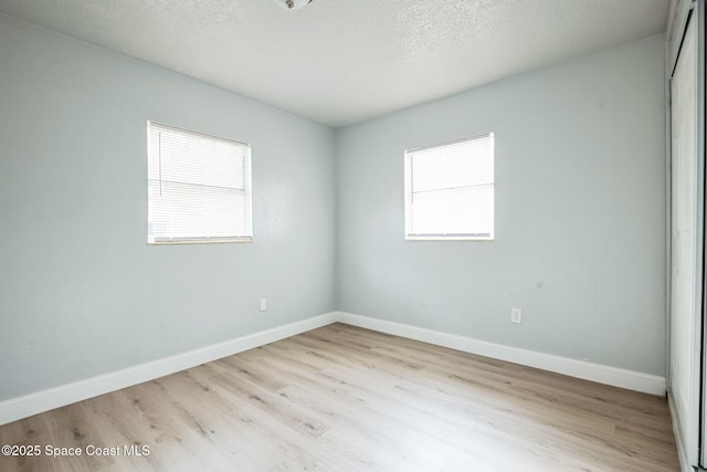 unfurnished room with a textured ceiling and light hardwood / wood-style floors