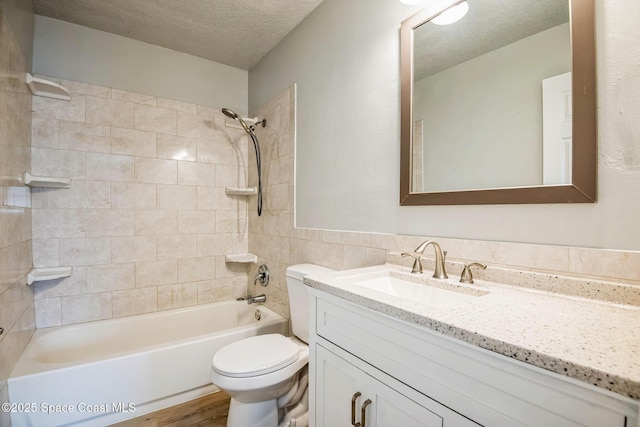 full bathroom with a textured ceiling, tiled shower / bath combo, wood-type flooring, vanity, and toilet