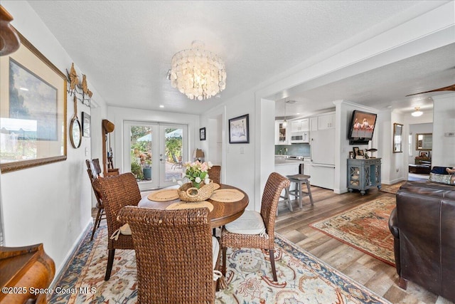 dining space with an inviting chandelier, hardwood / wood-style floors, a textured ceiling, and french doors