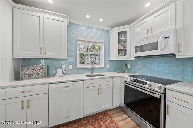 kitchen with tasteful backsplash, white cabinetry, sink, and white appliances