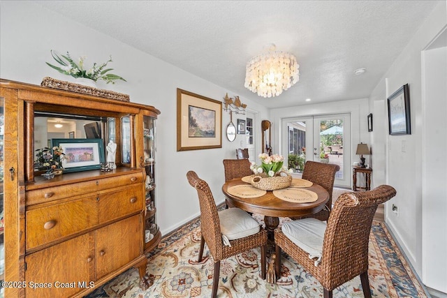 dining area featuring a textured ceiling, an inviting chandelier, and french doors