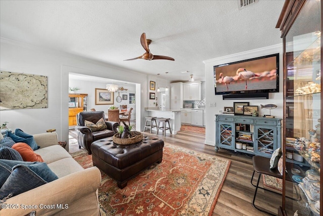 living room with ceiling fan, crown molding, hardwood / wood-style floors, and a textured ceiling