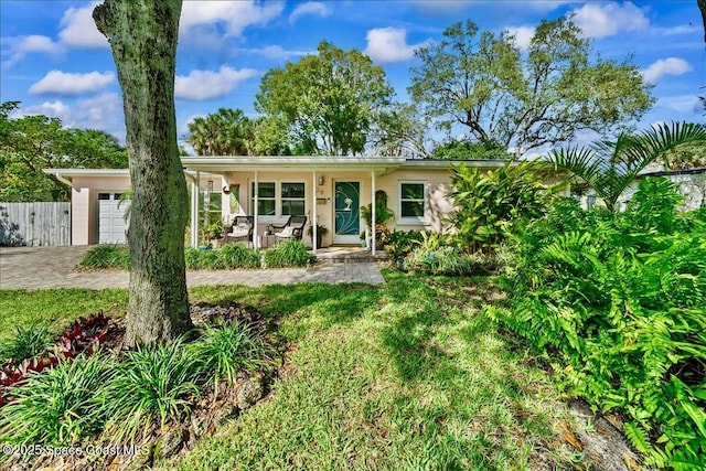 ranch-style home featuring a garage, a front yard, and a porch