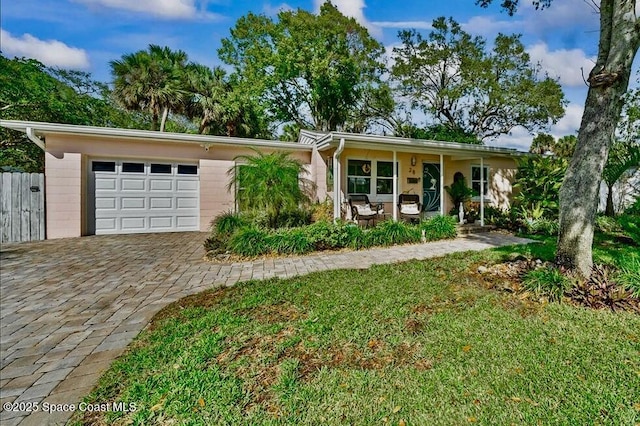 ranch-style house featuring a porch, a garage, and a front lawn