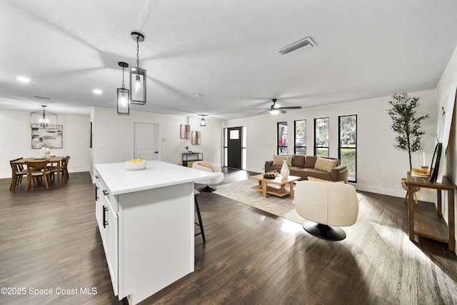 kitchen with a kitchen island, a kitchen bar, white cabinetry, hanging light fixtures, and ceiling fan