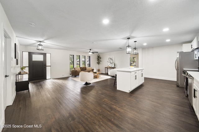 kitchen featuring a center island, decorative light fixtures, white cabinetry, dark hardwood / wood-style floors, and ceiling fan