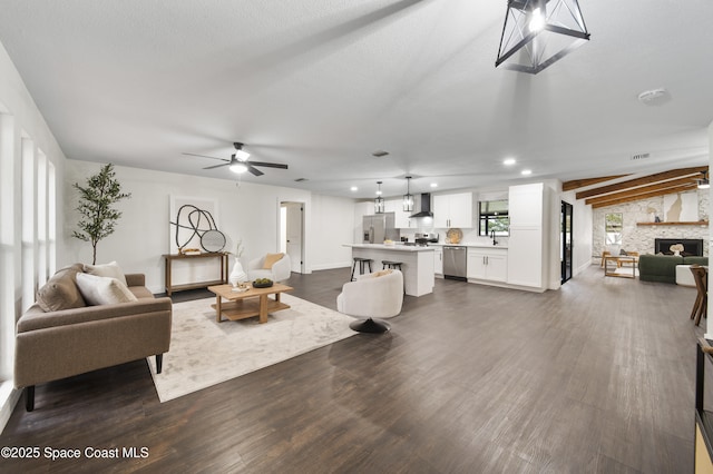 living room featuring ceiling fan, vaulted ceiling, dark hardwood / wood-style flooring, and a fireplace