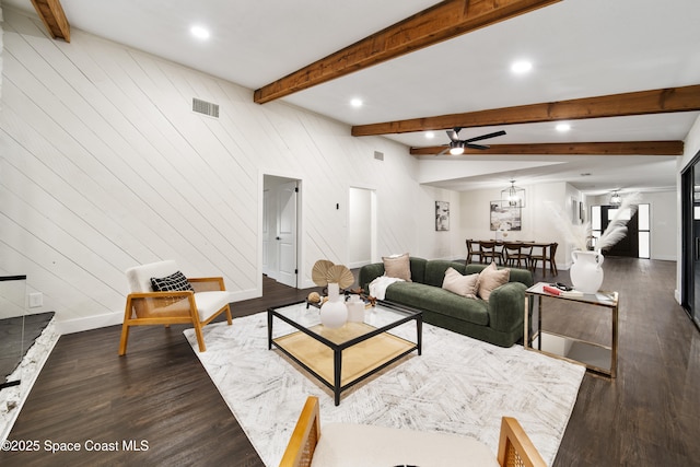 living room with dark wood-type flooring, beam ceiling, wooden walls, and ceiling fan