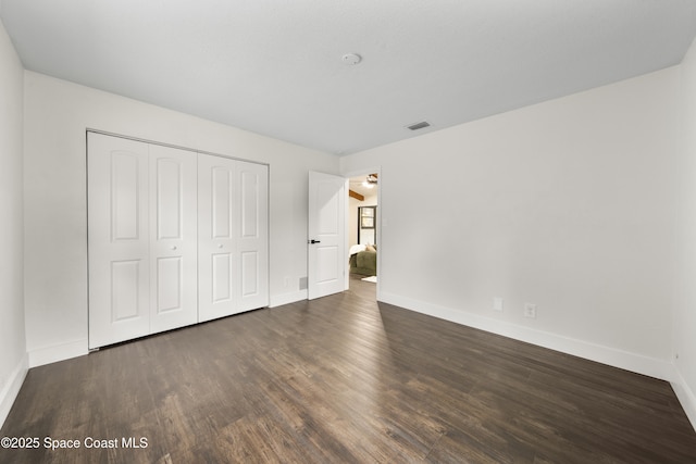 unfurnished bedroom with a closet and dark hardwood / wood-style flooring