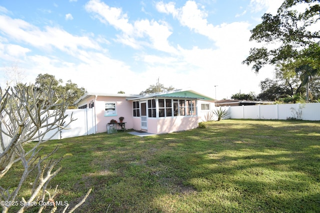 rear view of property featuring a sunroom and a yard