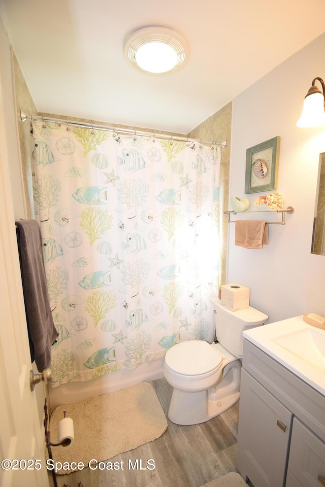 bathroom featuring toilet, wood-type flooring, vanity, and curtained shower