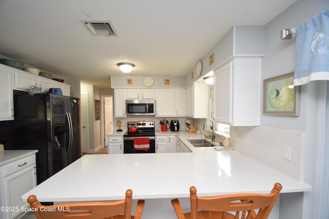 kitchen with white cabinetry, kitchen peninsula, stainless steel appliances, a breakfast bar, and sink