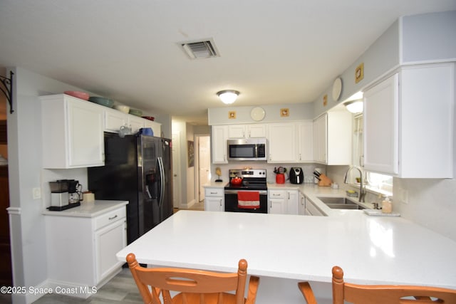 kitchen with a kitchen bar, sink, kitchen peninsula, and stainless steel appliances