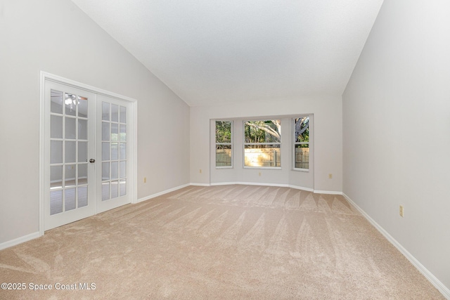 carpeted spare room with ceiling fan, french doors, and vaulted ceiling