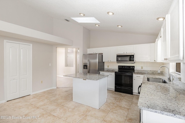 kitchen with a kitchen island, sink, white cabinetry, appliances with stainless steel finishes, and light stone counters