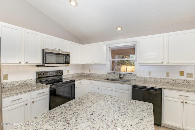 kitchen with lofted ceiling, black appliances, white cabinets, light stone counters, and sink