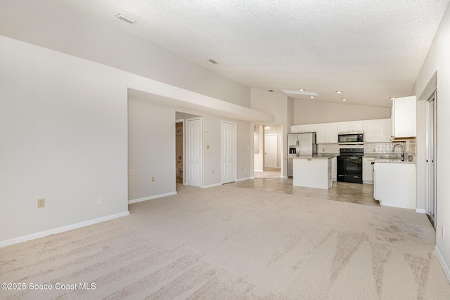 unfurnished living room with light colored carpet, a textured ceiling, lofted ceiling, and sink