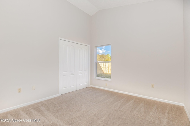 carpeted empty room with high vaulted ceiling