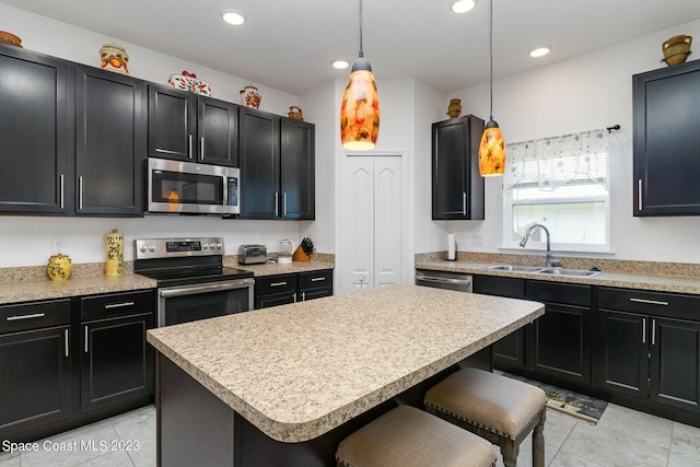 kitchen with a breakfast bar area, appliances with stainless steel finishes, sink, pendant lighting, and a center island