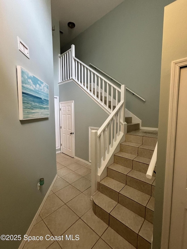 stairway featuring tile patterned floors and a high ceiling