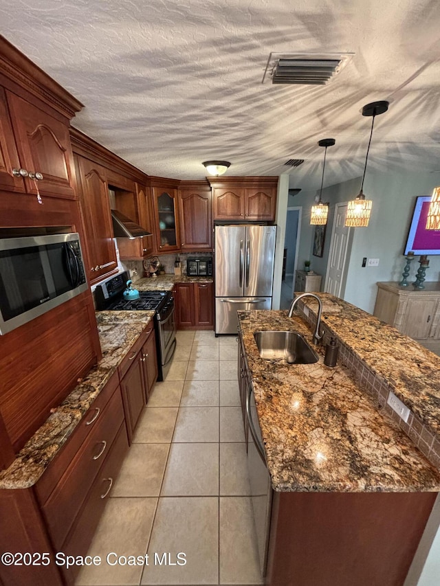 kitchen featuring decorative light fixtures, sink, light tile patterned floors, stainless steel appliances, and wall chimney exhaust hood