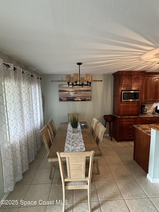 dining space with an inviting chandelier, a textured ceiling, and light tile patterned floors