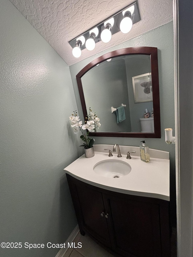 bathroom featuring vanity, a textured ceiling, and toilet