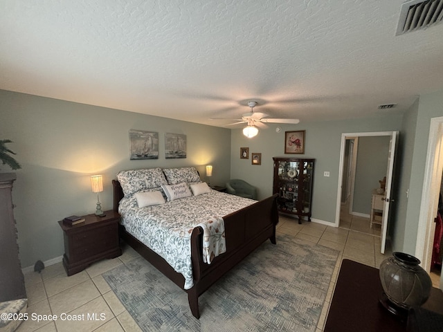 tiled bedroom with ceiling fan and a textured ceiling