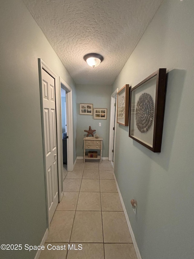 corridor featuring light tile patterned floors and a textured ceiling