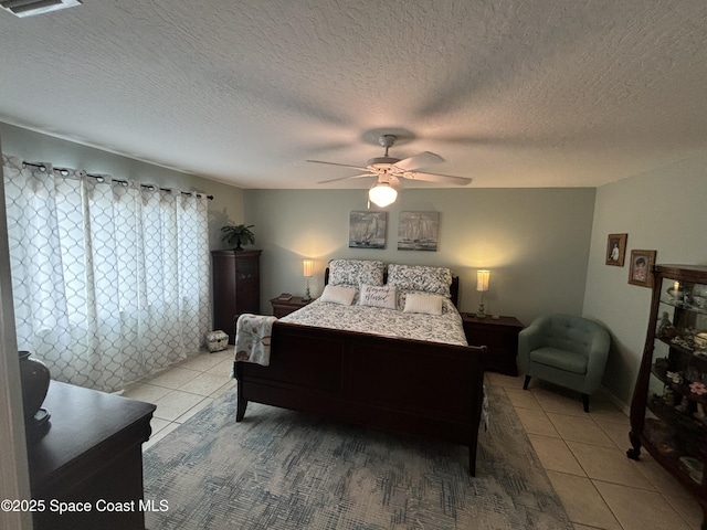 tiled bedroom with ceiling fan and a textured ceiling