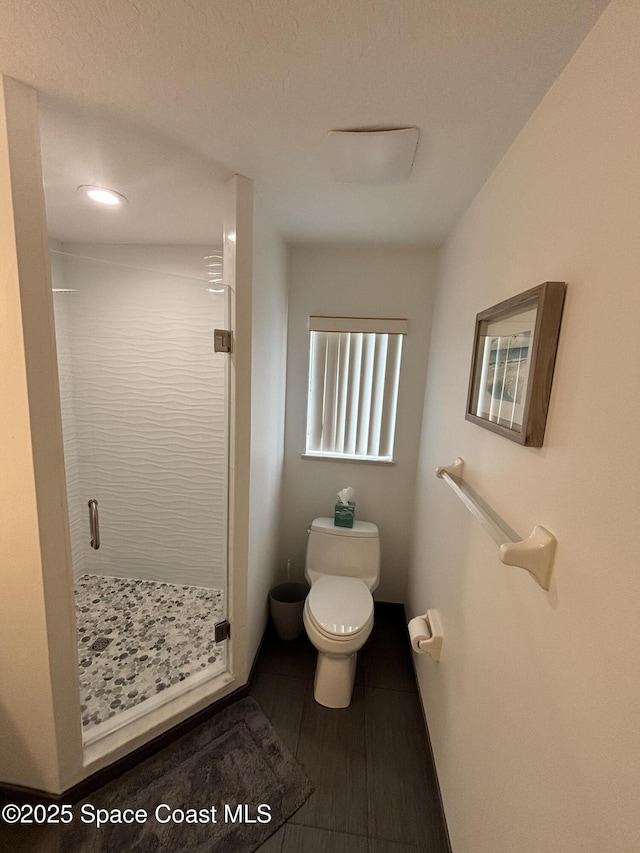 bathroom with wood-type flooring, tiled shower, and toilet