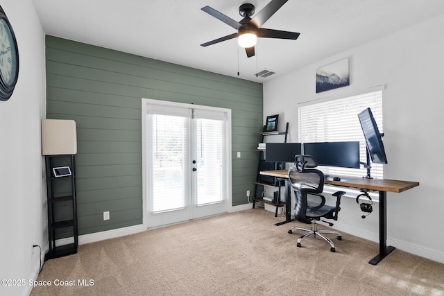 carpeted office featuring ceiling fan and wood walls