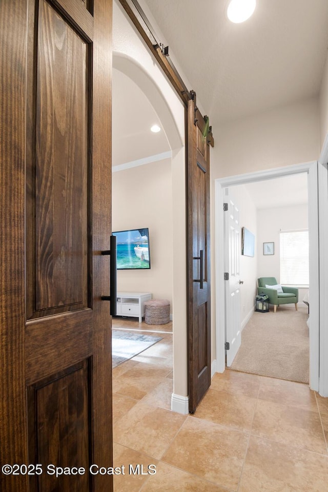 hall with a barn door and light carpet