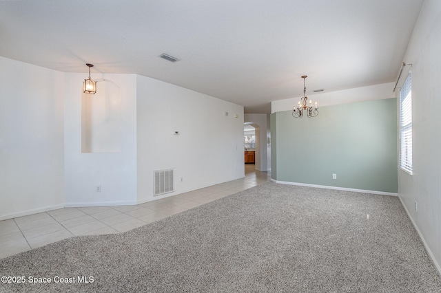 carpeted empty room featuring an inviting chandelier