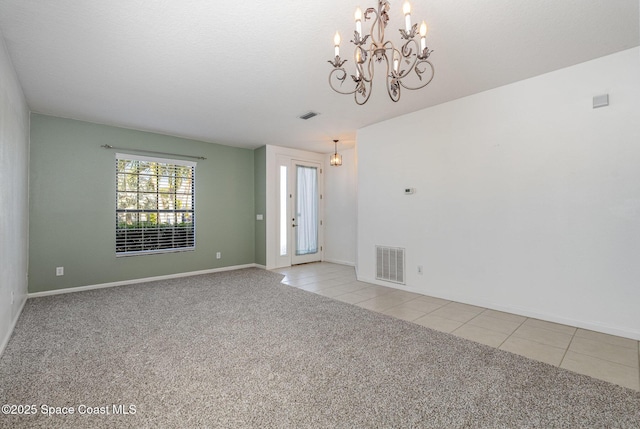 empty room with an inviting chandelier and light tile patterned floors