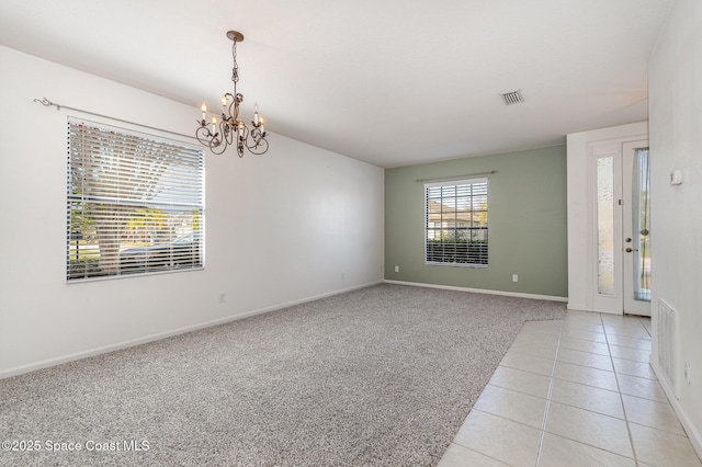 spare room featuring light carpet and a notable chandelier