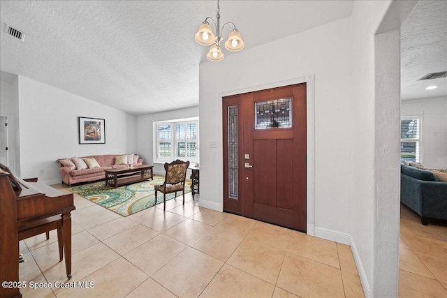 tiled entryway featuring lofted ceiling, a notable chandelier, and a textured ceiling