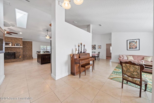 interior space with lofted ceiling with skylight, a fireplace, sink, light tile patterned floors, and a textured ceiling