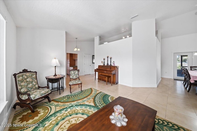 living room featuring light tile patterned floors, vaulted ceiling, and a textured ceiling