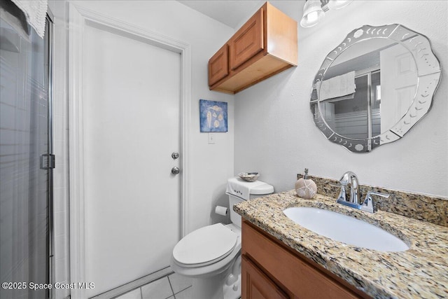 bathroom featuring tile patterned flooring, toilet, vanity, and a shower with shower door