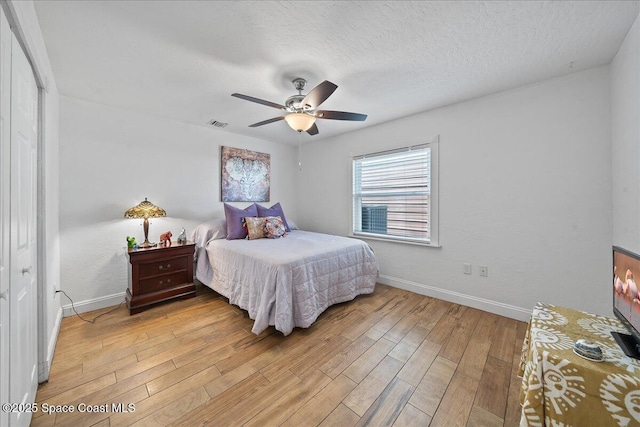 bedroom with ceiling fan, a textured ceiling, and light wood-type flooring